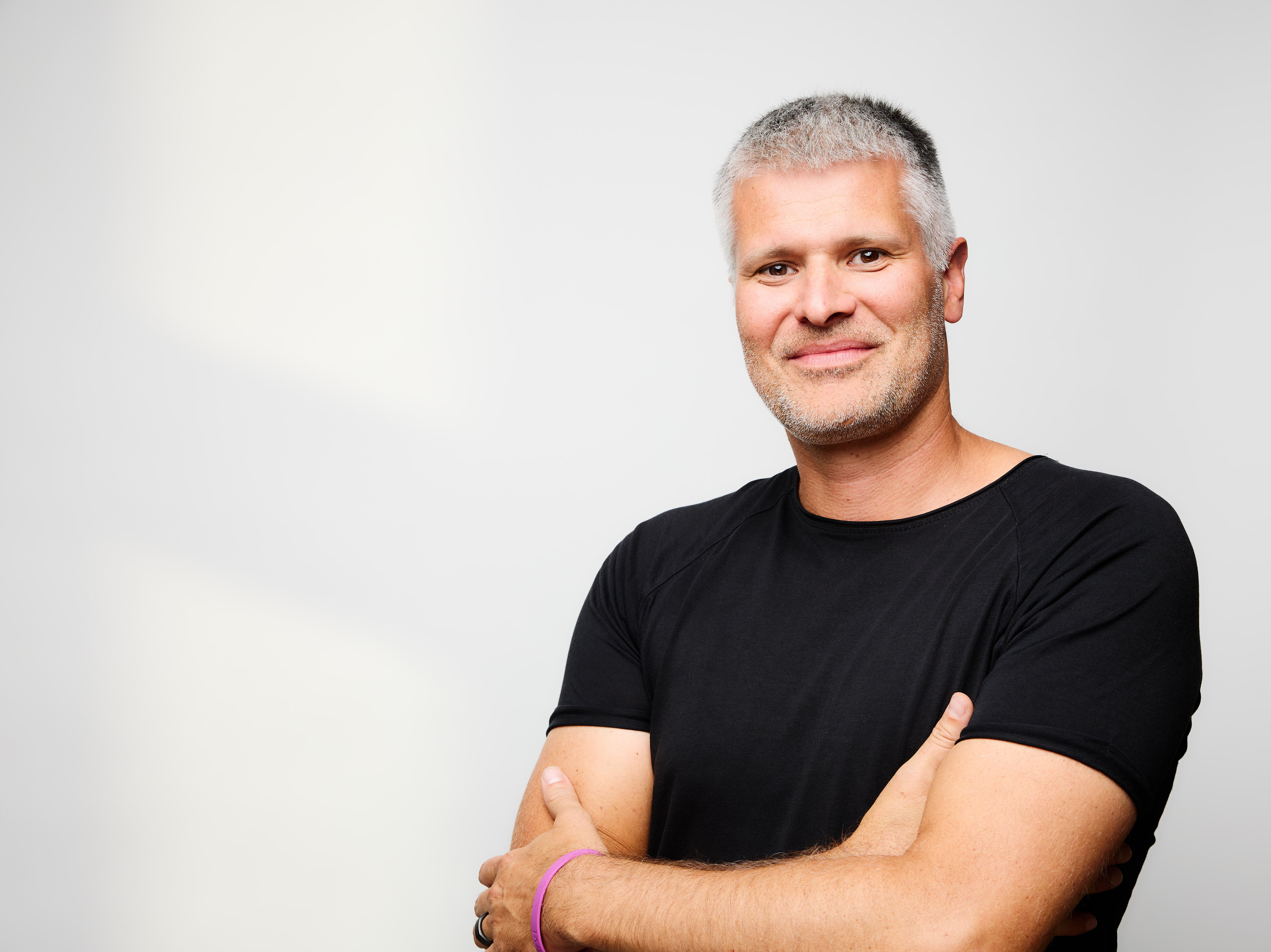 Portrait mit verschränkten Armen vor hellem Hintergrund